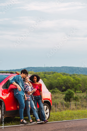 Happy multiracial friends taking a selfie on the road.