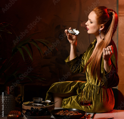 Tablou pe pânză Rich wealthy red-haired woman is sitting on table laid served with oysters, seaf