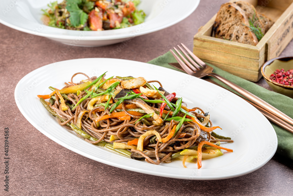 Buckwheat noodles with fresh vegetables in a white oval plate
