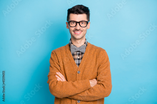 Photo of cheerful funny young man hand wear brown cardigan spectacles arms crossed isolated blue color background