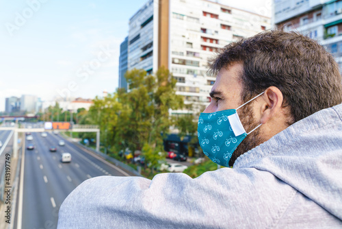 Horizontal view of unrecognizable young man wearing a face mask walking in the street. Urban city and people depressed by covid 19 pandemic disease. Depression caused by sanitary confinement.