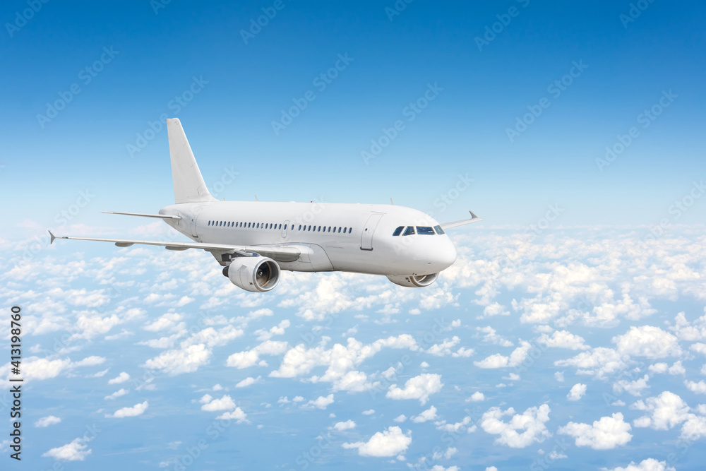 Fototapeta premium Airplane fly over the clouds and the earths surface under the blue sky.