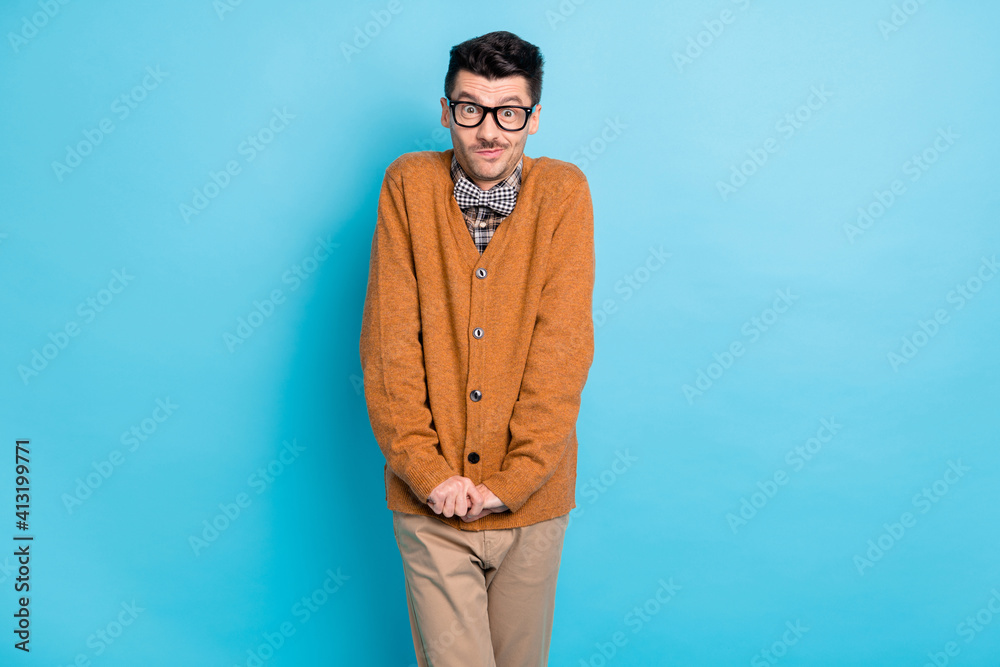Photo of timid funky young man hold hands together shy guy isolated on pastel blue color background Photo of timid funky young man hold hands together shy guy isolated on pastel blue color background