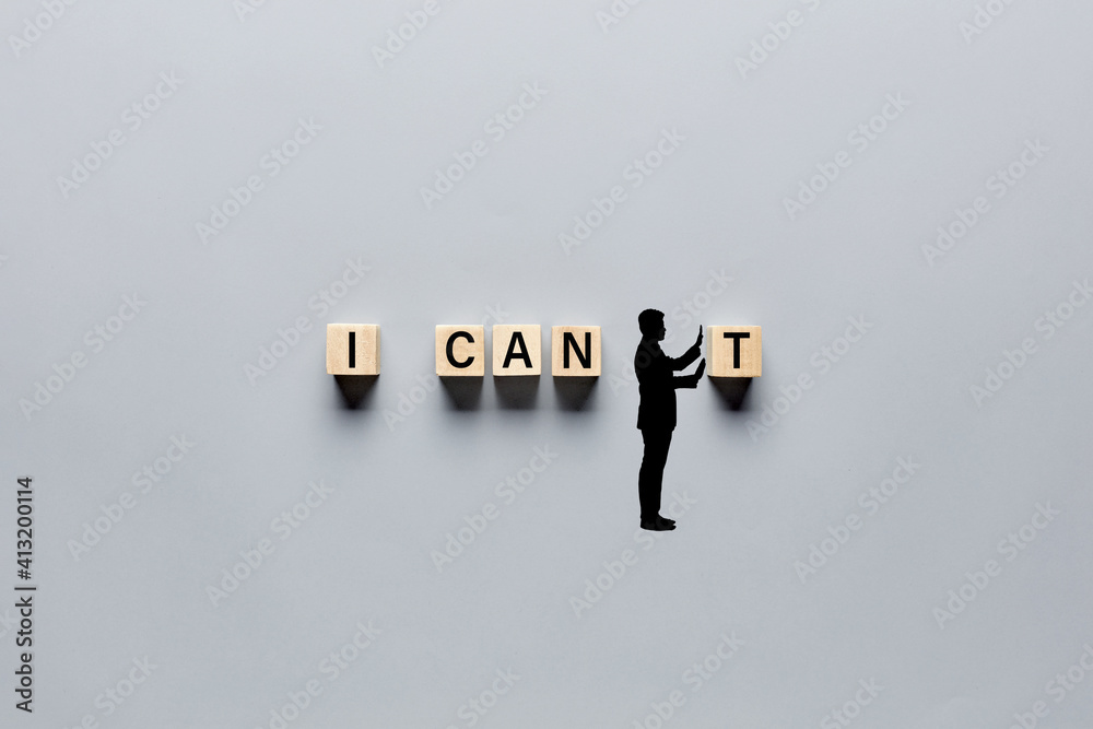Fototapeta premium Silhouette of a man changing the word I can't into I can by pushing away the letter. Aspiration, positivity, belief and motivation