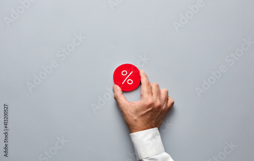 Businessman hand holding a red badge with a percent sign. Business discount, interest, mortgage or profit rate