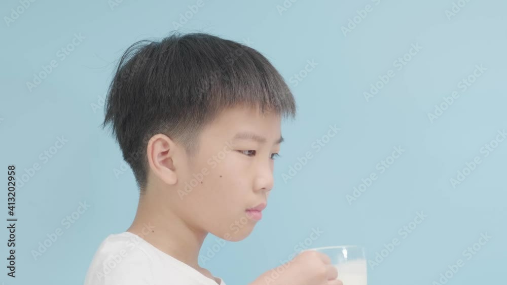 Selective focus young Asian boy milk from glass on blue background Selective focus young Asian boy milk from glass on blue background