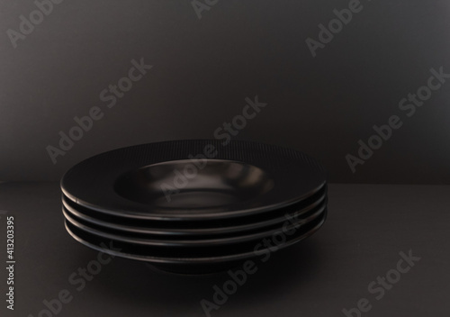 A simple composition of a stack of black plates on a black background.