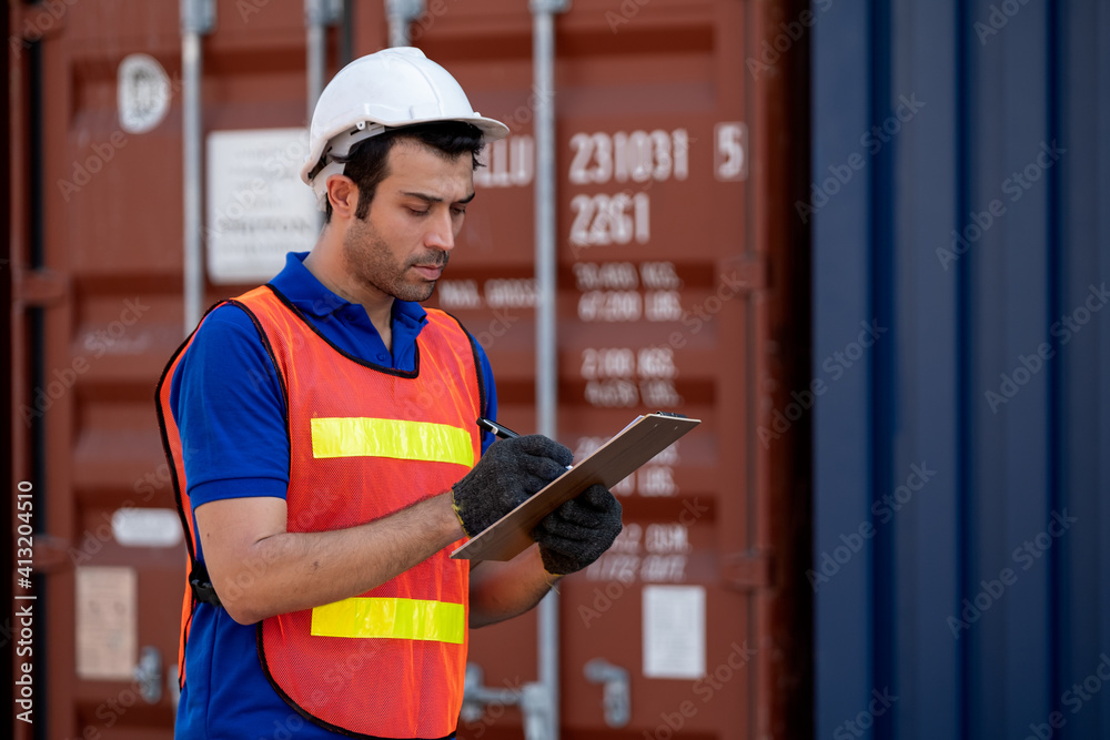 One foreman or engineer cargo container worker hold and record data in clipboard and also looking to the data in workplace area. Industrial data for factory or logistic business concept.
