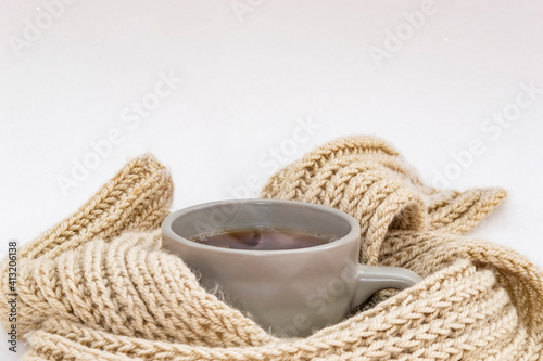 Hot tea with steam in a gray mug on the snow. 