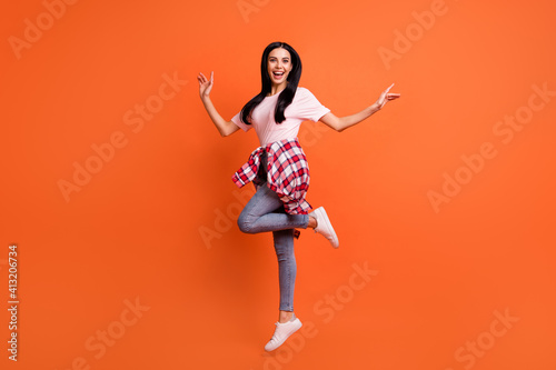 Fototapeta Naklejka Na Ścianę i Meble -  Full length profile photo of cheerful nice lady jumping hands sides beaming smile isolated on orange color background