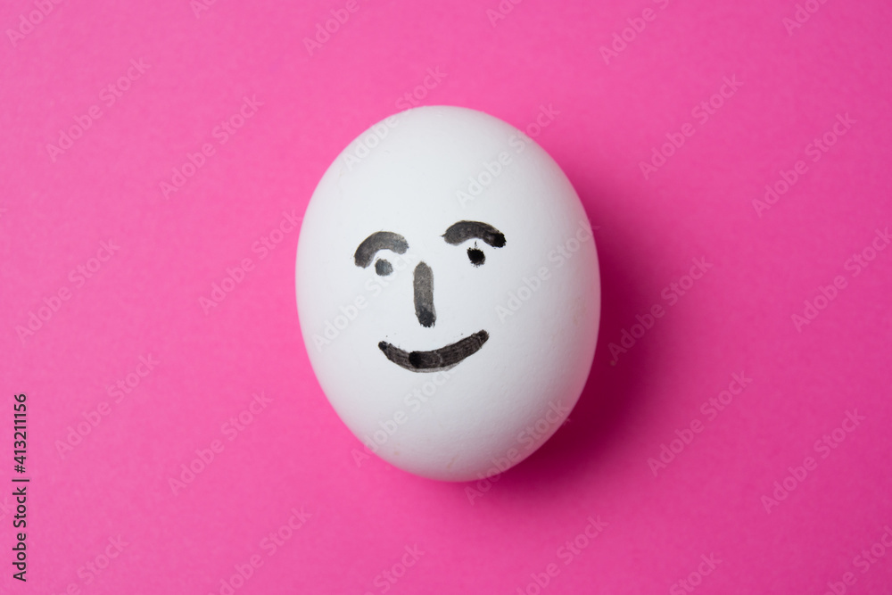 Fototapeta premium Egg with a happy face on a pink background with copy space.