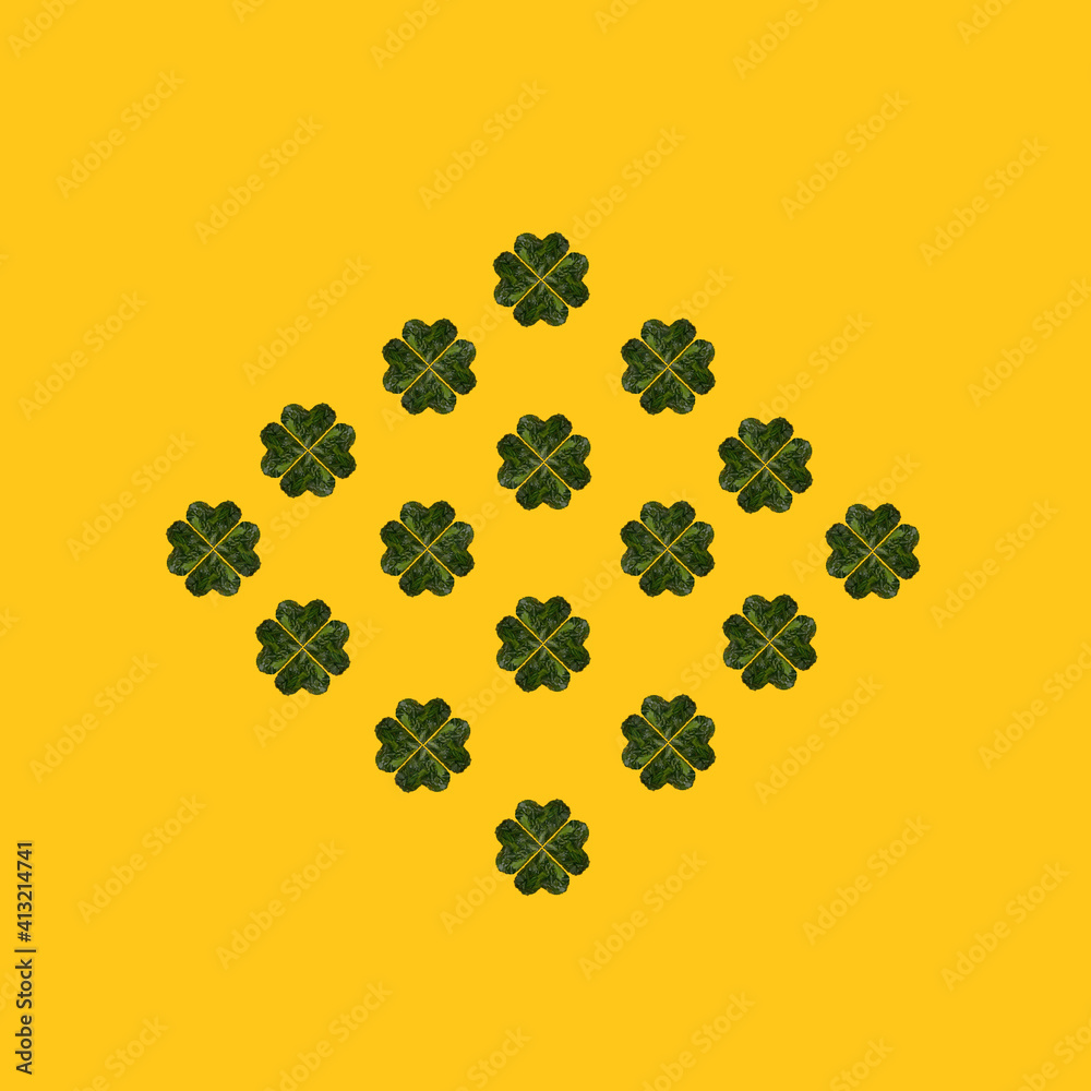 Naklejka premium Pattern created of minimal lucky shamrock arranged from hearts formed of fresh green leaves from Irish woods. Clovers shape leaves are against yellow background from flat lay.