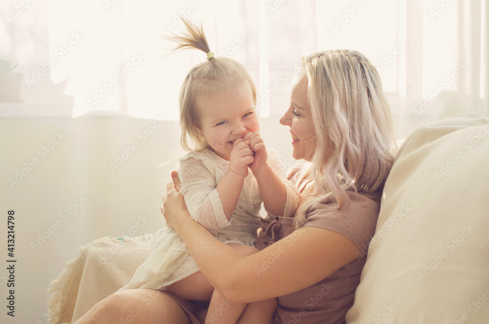Mother and daughter toddler playing, kissing, hugging and smiling, enjoy at the sofa, spending time at home. Moments of tenderness . Happy loving family. Good time at home. Family single mother Mother and daughter toddler playing, kissing, hugging and smiling, enjoy at the sofa, spending time at home. Moments of tenderness . Happy loving family. Good time at home. Family single mother