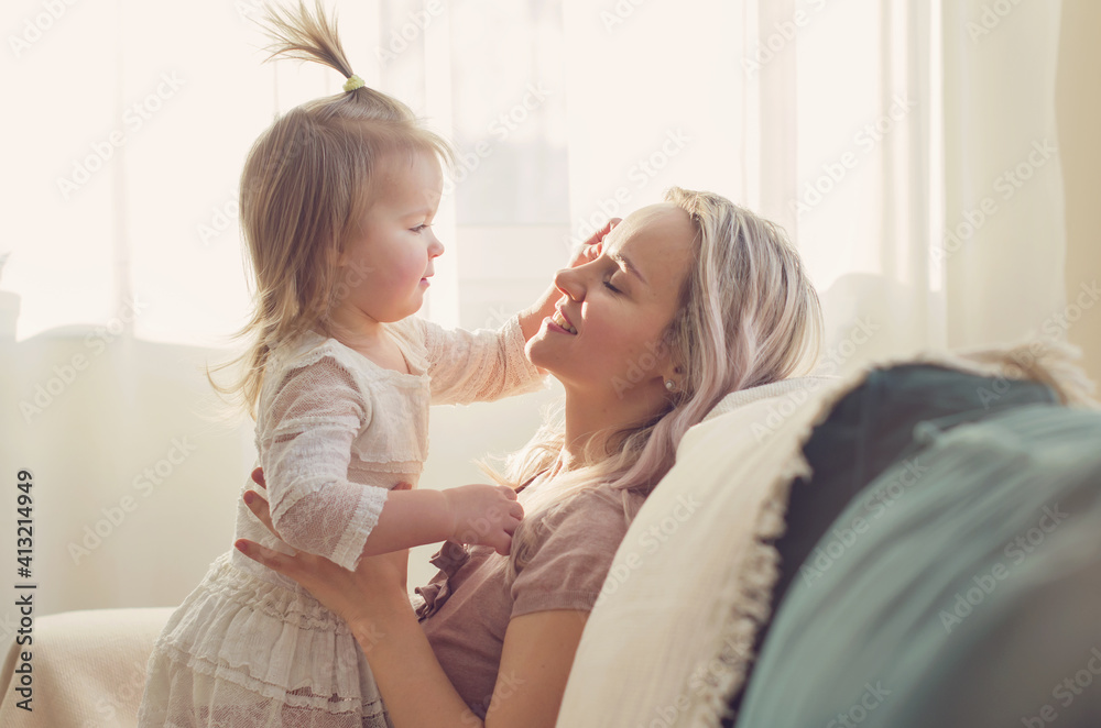 Mother and daughter toddler playing, kissing, hugging and smiling, enjoy at the sofa, spending time at home. Moments of tenderness . Happy loving family. Good time at home. Family single mother Mother and daughter toddler playing, kissing, hugging and smiling, enjoy at the sofa, spending time at home. Moments of tenderness . Happy loving family. Good time at home. Family single mother