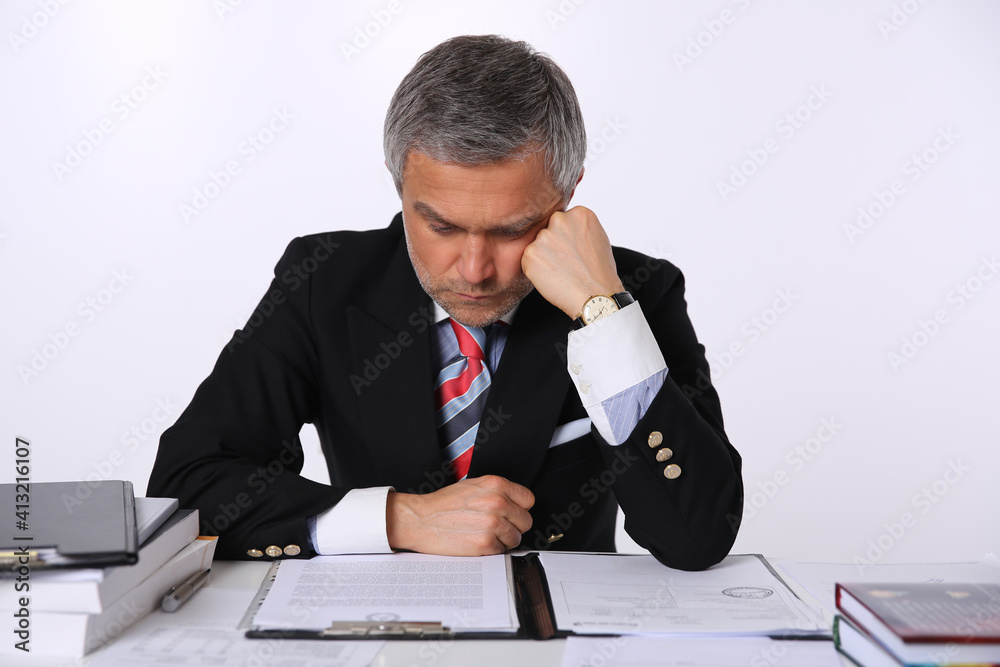A businessman with documents at the table.
A businessman with documents at the table.