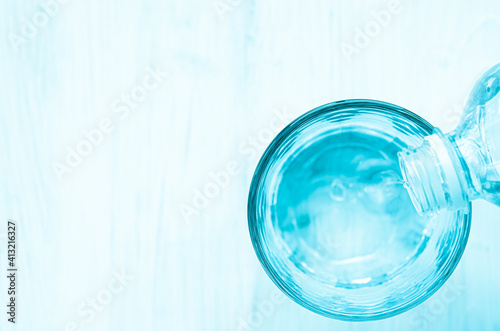 Pouring water from bottle into glass on background