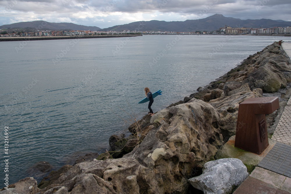 Mujer surfista entrando al agua para surfear en Hondarribia