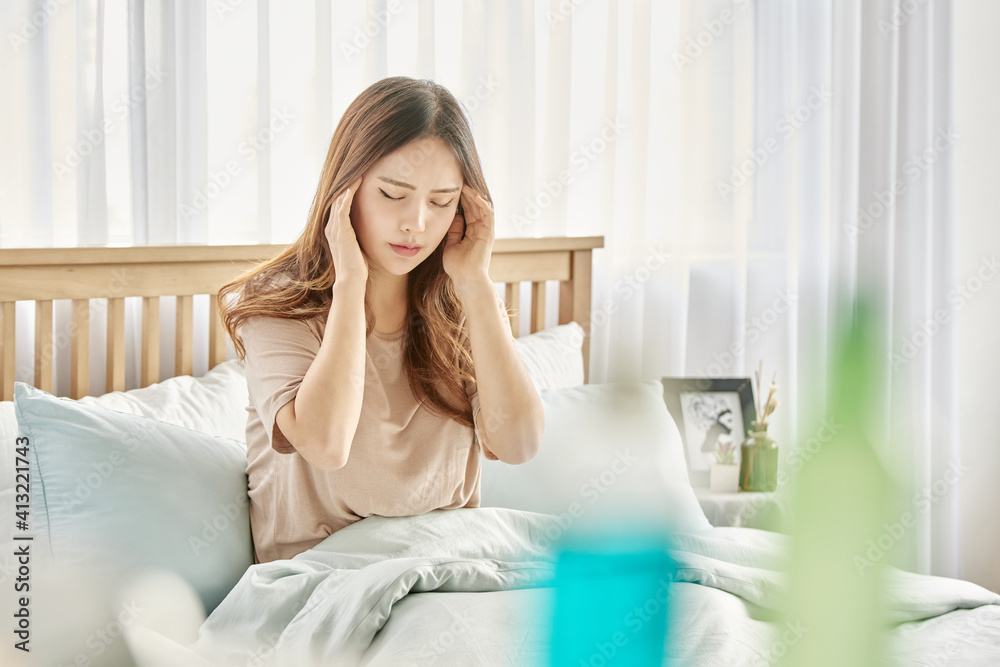 감기와 두통으로 침대에 앉아 있는 여자 감기와 두통으로 침대에 앉아 있는 여자