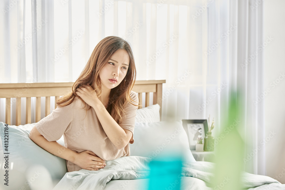 감기와 두통으로 침대에 앉아 있는 여자 감기와 두통으로 침대에 앉아 있는 여자
