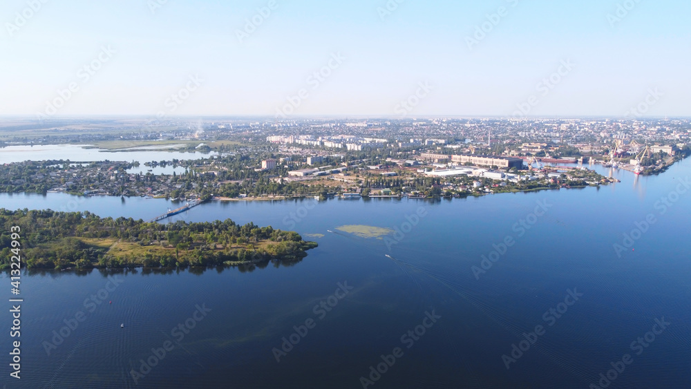 Drone fly over waving river of blue color surrounded by local village with various buildings and Wetland and marsh habitat with a reedbed of Common Reed aerial view.