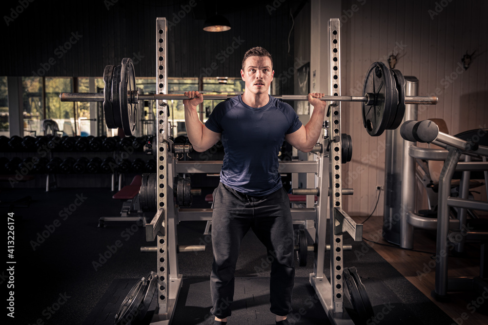 male athlete is lifting a barbell in a fitness center, doing his daily workout male athlete is lifting a barbell in a fitness center, doing his daily workout