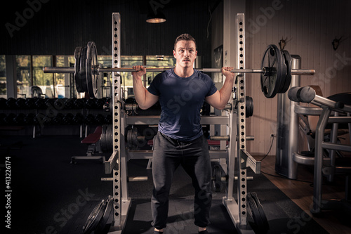 male athlete is lifting a barbell in a fitness center, doing his daily workout