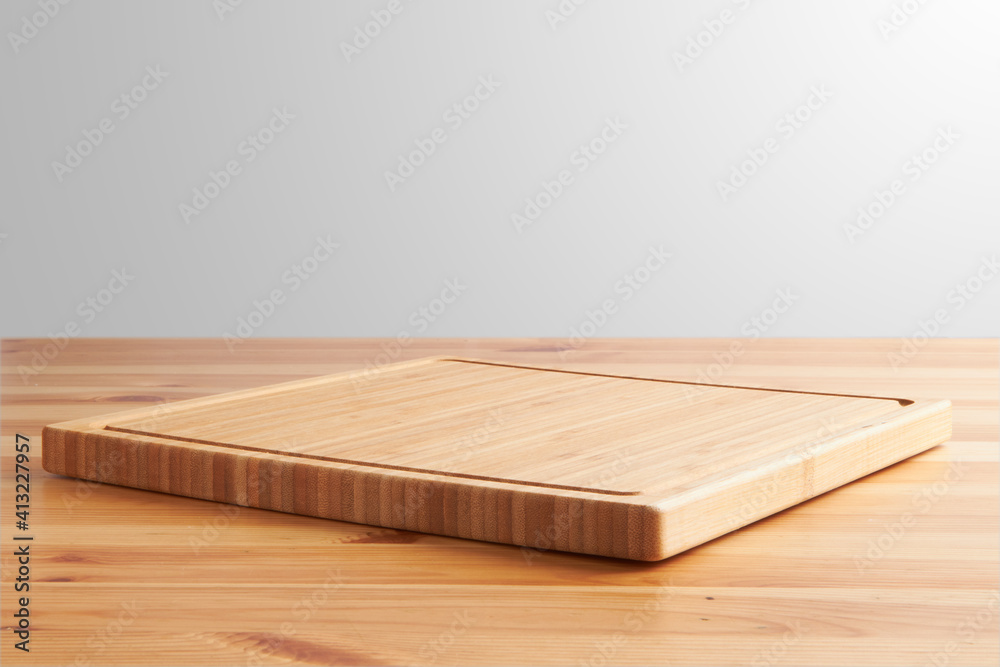 new rectangular wooden cutting board, in top of wooden table with a minimalistic limbo background new rectangular wooden cutting board, in top of wooden table with a minimalistic limbo background