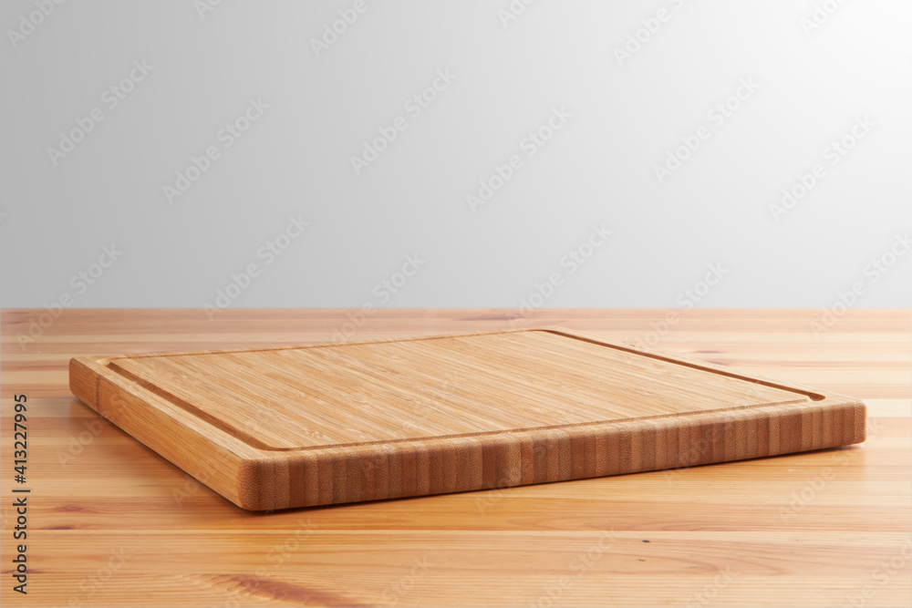 new rectangular wooden cutting board, in top of wooden table with a minimalistic limbo background