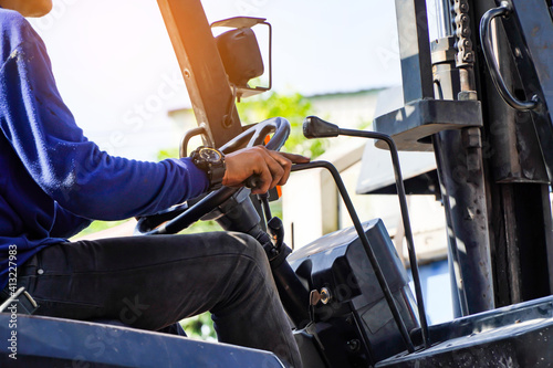 Asian male worker drives a forklift in an industrial factory. This is distribution and warehouse. Concept of industrial and industrial workers