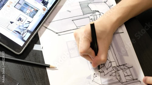 The hand of an architect drawing a perspective of the bedroom with a black pen. On a black wooden desk where a tablet and pencil are placed. timelapse photo