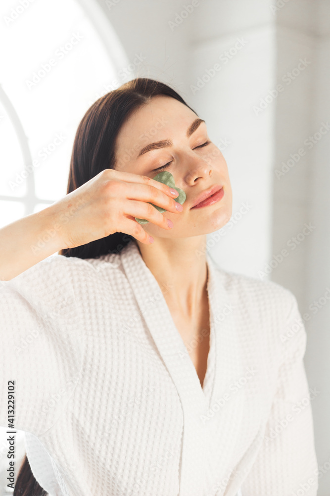 Young woman doing face Gua sha - chinese traditional massage Young woman doing face Gua sha - chinese traditional massage