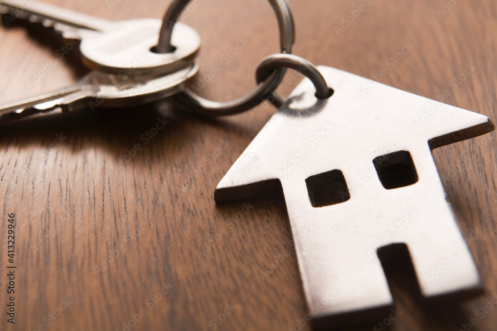 Home Ownership Concept With Metal House Shaped Key Ring On Wooden Surface Home Ownership Concept With Metal House Shaped Key Ring On Wooden Surface