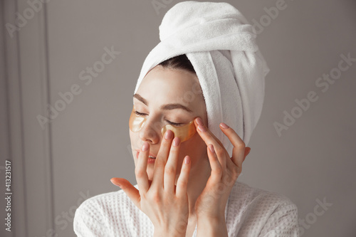 Foto Pretty european girl applying golden collagen patches under her eyes