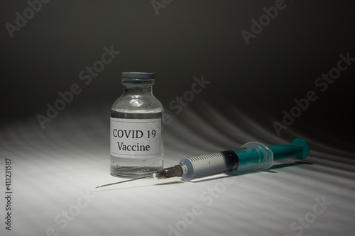 Covid 19 vaccine bottle and syringe on a black background.