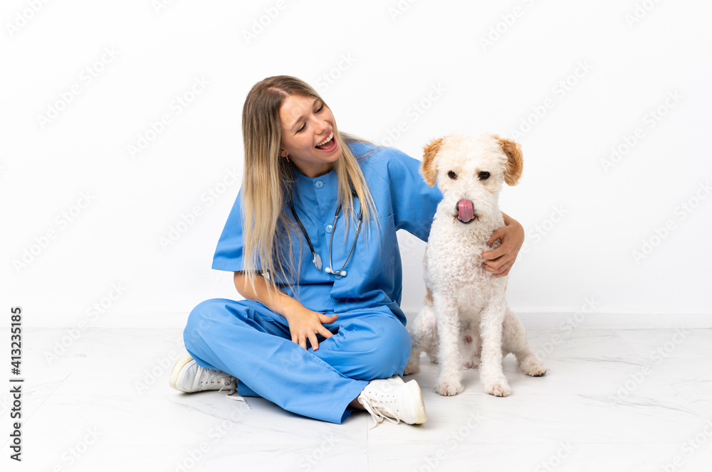 Young veterinarian woman with dog sitting on the floor laughing in lateral position Young veterinarian woman with dog sitting on the floor laughing in lateral position
