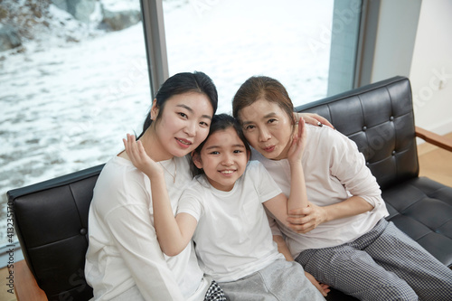 Little kid daughter and old mother while sitting on sofa at home © stciel
