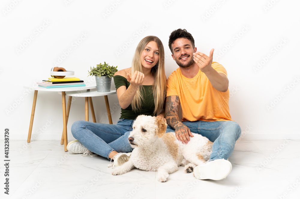 Young caucasian couple with dog staying at home inviting to come with hand Young caucasian couple with dog staying at home inviting to come with hand