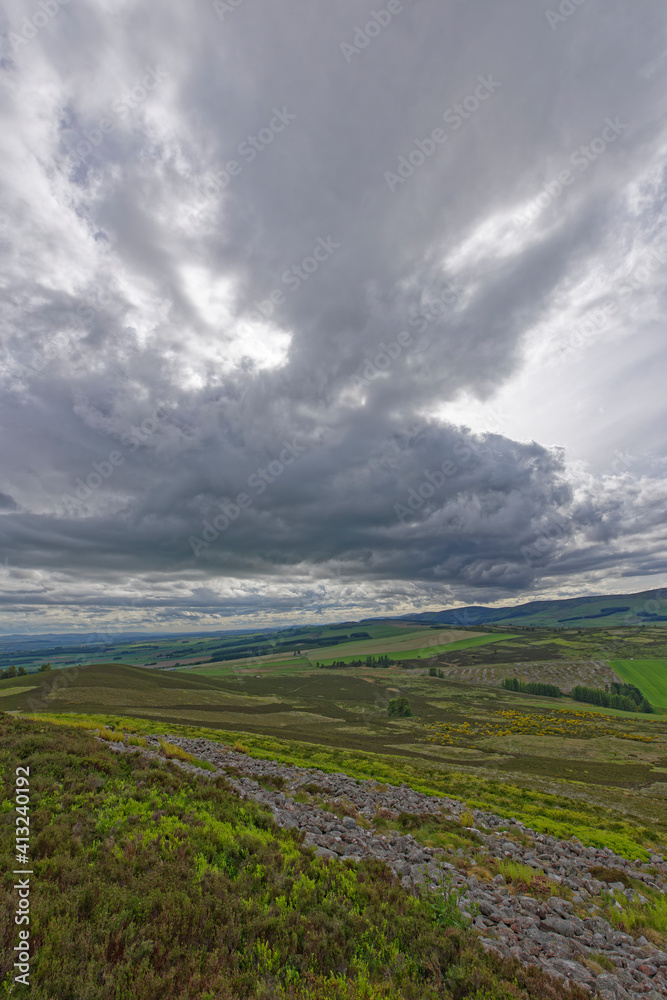 Looking south over the remains of the stone ramparts of the White Caterthun tothe Angus Glens with dark clouds of a Weather front above. Looking south over the remains of the stone ramparts of the White Caterthun tothe Angus Glens with dark clouds of a Weather front above.