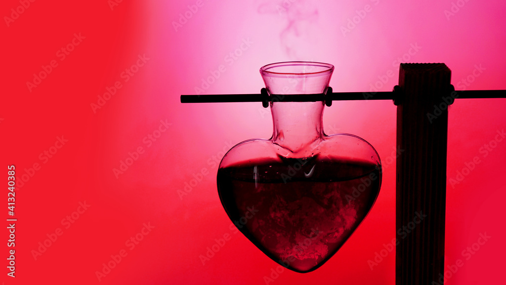 Open heart-shaped bottle of red love potion on a blurredred and pink background
