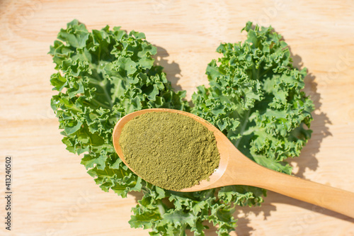 Green kale powder in a wooden spoon background  Leaf on wooden table
