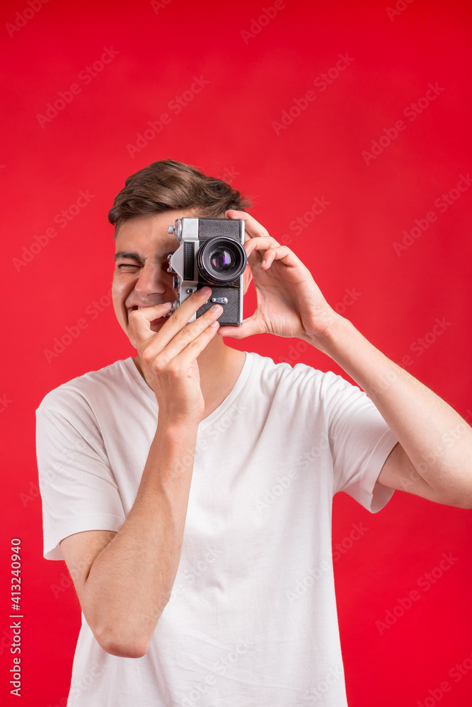 Say cheese! Young man take photo with retro dslr camera looking at camera over gray abackground. Portrait of positive man in hat with retro camera standing isolated