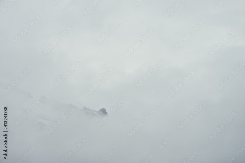 Minimal mountain landscape with high pointy rock in clouds. Minimalist mountain scenery with sharp snowy mountain peak over clouds. Snow-white pointed pinnacle above white clouds. Big top in dense fog Minimal mountain landscape with high pointy rock in clouds. Minimalist mountain scenery with sharp snowy mountain peak over clouds. Snow-white pointed pinnacle above white clouds. Big top in dense fog
