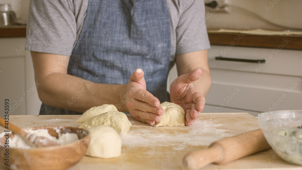 A man rolls dough on the table in the kitchen. Homemade bread baking A man rolls dough on the table in the kitchen. Homemade bread baking