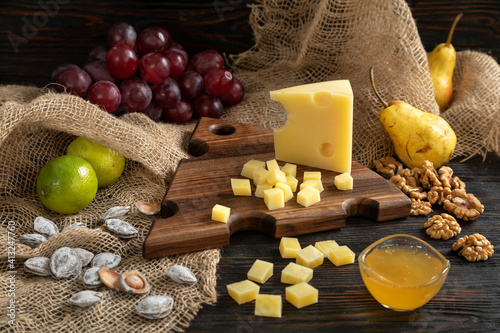 Obraz na płótnie Cheese, pears and nuts on a wooden cutting board w salonie