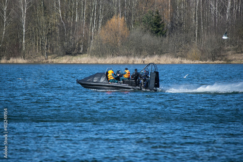 A black lifeboat with an air motor floats fast on the lake. Training of rescuers of Belarus in early spring.