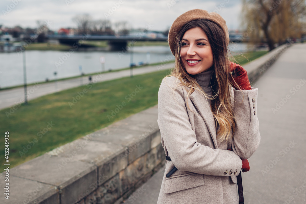 Fototapeta premium Stylish woman tourist walking along pier by Wisla river in Krakow, Poland enjoying landscape. Europe spring trip