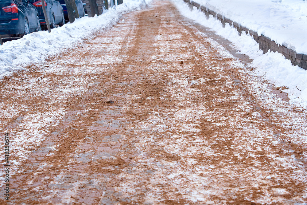 Spreading sand and salt on pavement to increase friction of icy road