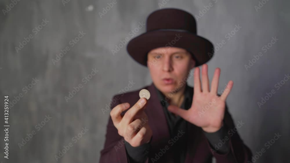 Portrait of a magician biting a coin, standing on the background. Inflation concept. The magician bites off a coin. Portrait of a magician biting a coin, standing on the background. Inflation concept. The magician bites off a coin.