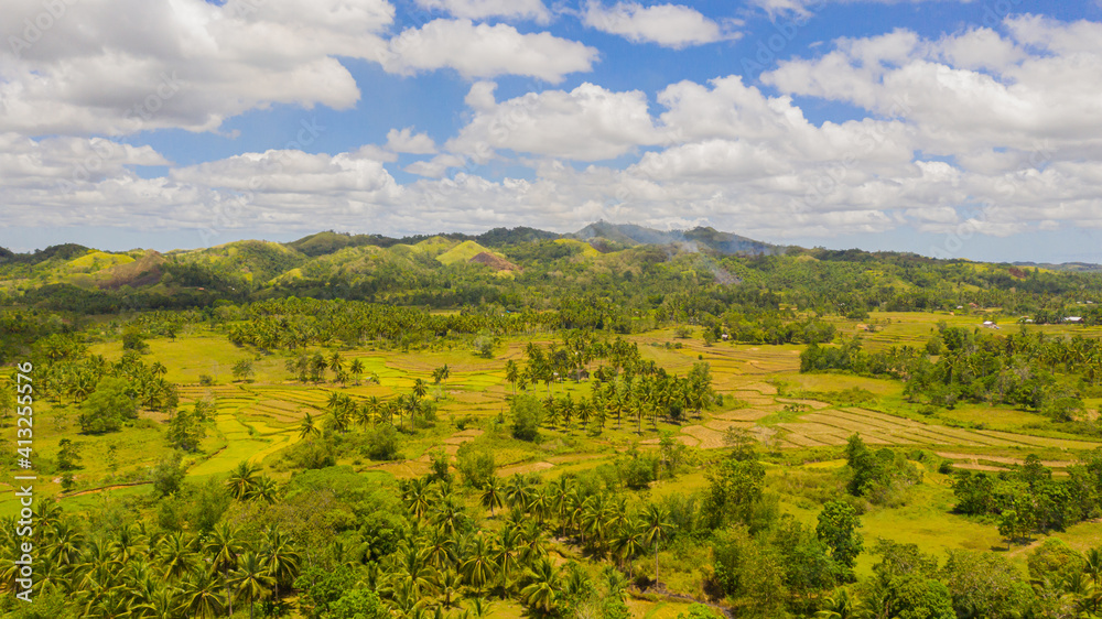 Mountain slopes and hills with tropical vegetation under a blue sky with clouds. Bohol, Philippines.
