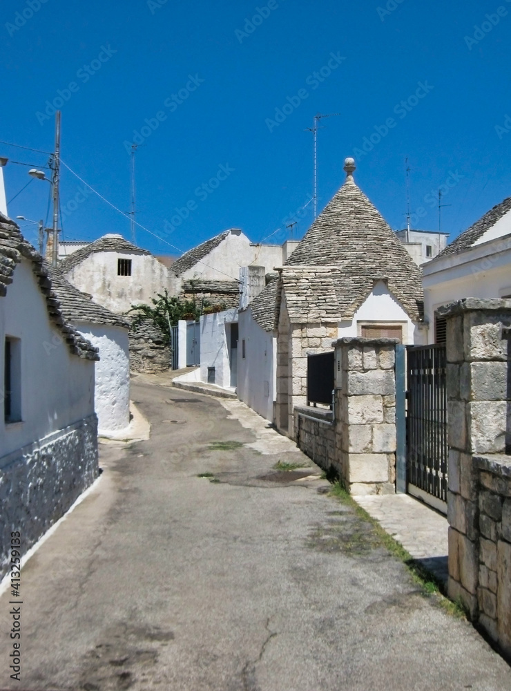 View of the road in the historic center of Alberobello. White houses. Trullo roofs. Apulia. Italy. Europe